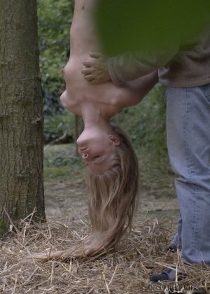Young blonde girl has her hair pull after being suspended upside down in woods